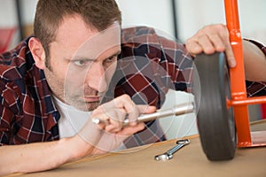 concentrated man fixing trolley wheel