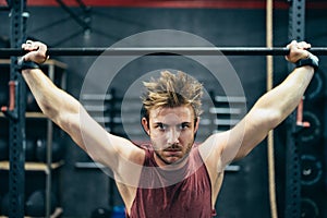 Concentrated man lifting a barbell in a gym