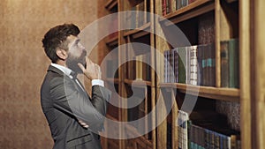 Concentrated man in the old library. Classic vintage interior. Law and justice concept. Man picking a book in a library.