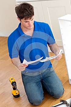 Concentrated man reading instructions of furniture