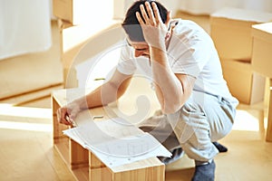 Concentrated man reading instructions to assemble furniture at home