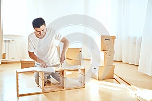 Concentrated man reading instructions to assemble furniture at home