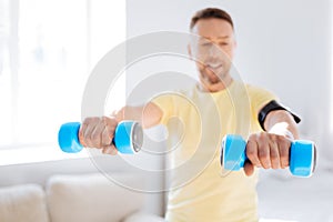 Concentrated man rising dumbbells