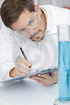 concentrated man scientist taking notes in lab