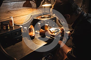 Concentrated man shoemaker at footwear workshop.