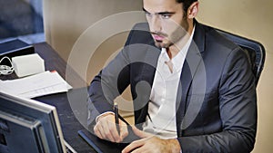 Concentrated man using graphic tablet in office