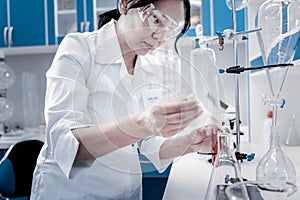 Concentrated mature lady conducting chemical experiment