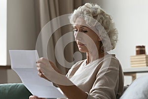 Concentrated mature woman read postal letter at home