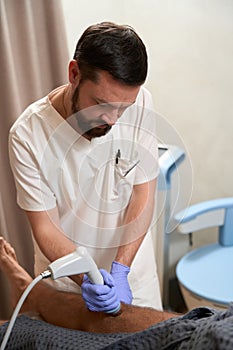 Concentrated medic treating his patient with radiofrequency therapy