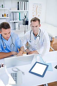 Concentrated medical colleagues discussing and working with laptop