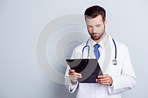 Concentrated medico in uniform holding clipboard and reading inf photo