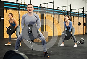 Concentrated middle-aged man performing T-Bar row at gym