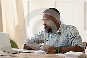 Concentrated millennial african american guy focused on online university courses.