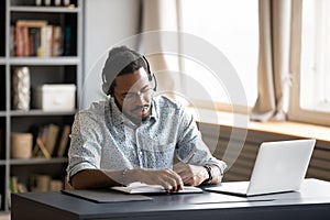Concentrated biracial guy listening to favorite music while planning workday. photo