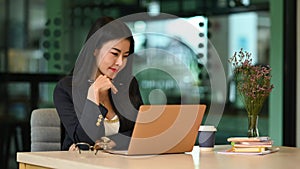 Concentrated millennial businesswoman reading business email or financial information on laptop computer