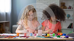 Concentrated multiracial friends painting at art school, preschool education