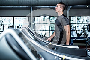 Concentrated muscular man using treadmill
