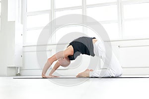 concentrated muscular yogi man working out, bending in Little Thunderbolt Pose or Laghu Vajrasana in studio