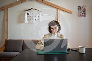 Concentrated on online study student girl sitting at desk with laptop watching webinar education.