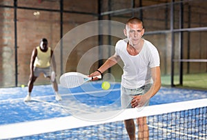 Concentrated paddle tennis player preparing to hit forehand