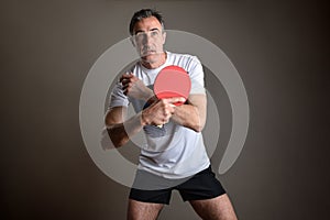 Concentrated ping-pong player waiting to receive a ball on gray