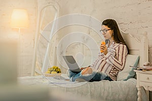 Concentrated pregnant woman working remotely at home