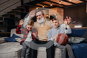 Concentrated senior bearded grandpa with his happy grandsons spending their leisure at revision the basketball