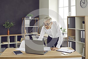 Concentrated senior European businessman while working with laptop computer in office.