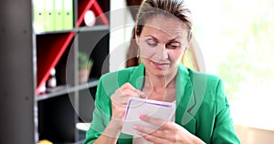 Concentrated serious woman thinks business ideas and writes information in notebook