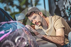 Concentrated service station worker washing a client vehicle