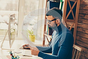 Concentrated smart bearded businessman in glasses reading contract