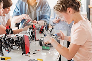 Concentrated smiling girl creating technical toy photo