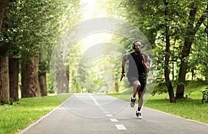 Concentrated sportsman running by park path in summer