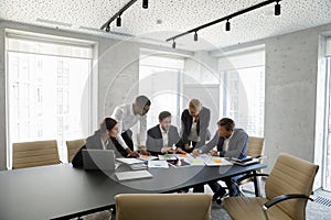 Concentrated successful happy diverse colleagues analyzing financial paper documents.