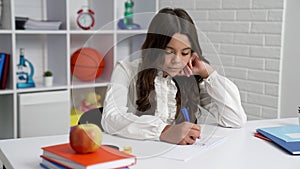 concentrated teen girl in school uniform studying in writing, concentration