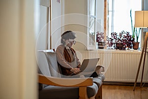 Concentrated teen girl working, studying at home in comfortable conditions using laptop computer