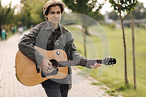 Concentrated teenage boy musician playing acoustic guitar outdoor. Handsome boy love misuc