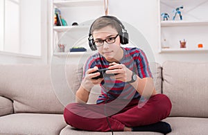 Concentrated teenage boy playing video game at home