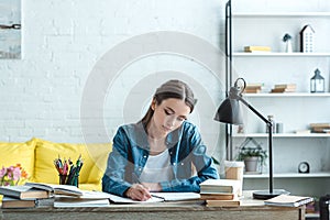 concentrated teenage girl writing and studying at desk
