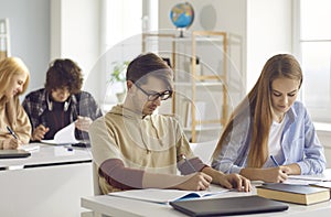 Concentrated teenager students group writing exam taking test in classroom