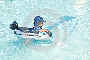 Concentrated toddler boy swimming in inflatable ring in pool