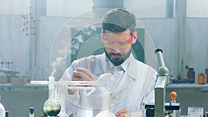 Concentrated upset scientist student doing some experiments in the chemistry laboratory he add some chemical liquid to