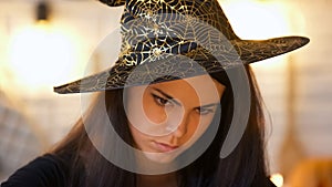 Concentrated witch in hat conjuring, black magic, costume Halloween party