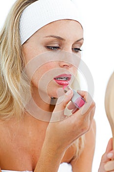 Concentrated woman applying lipstick