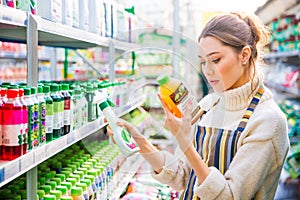 Concentrated woman choosing agricultural chemicals for flowers and plants