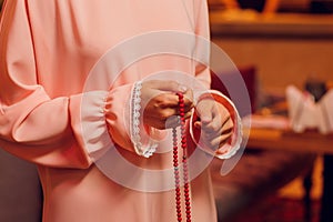 Concentrated woman praying wearing rosary beads. Namaste. Close up hands.