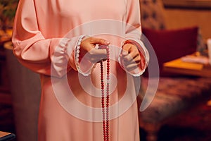 Concentrated woman praying wearing rosary beads. Namaste. Close up hands.