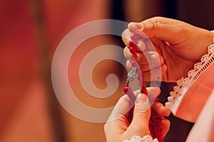 Concentrated woman praying wearing rosary beads. Namaste. Close up hands.