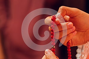 Concentrated woman praying wearing rosary beads. Namaste. Close up hands.