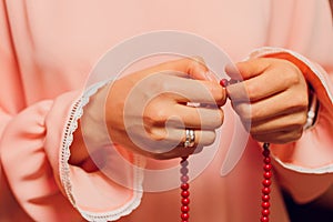 Concentrated woman praying wearing rosary beads. Namaste. Close up hands.